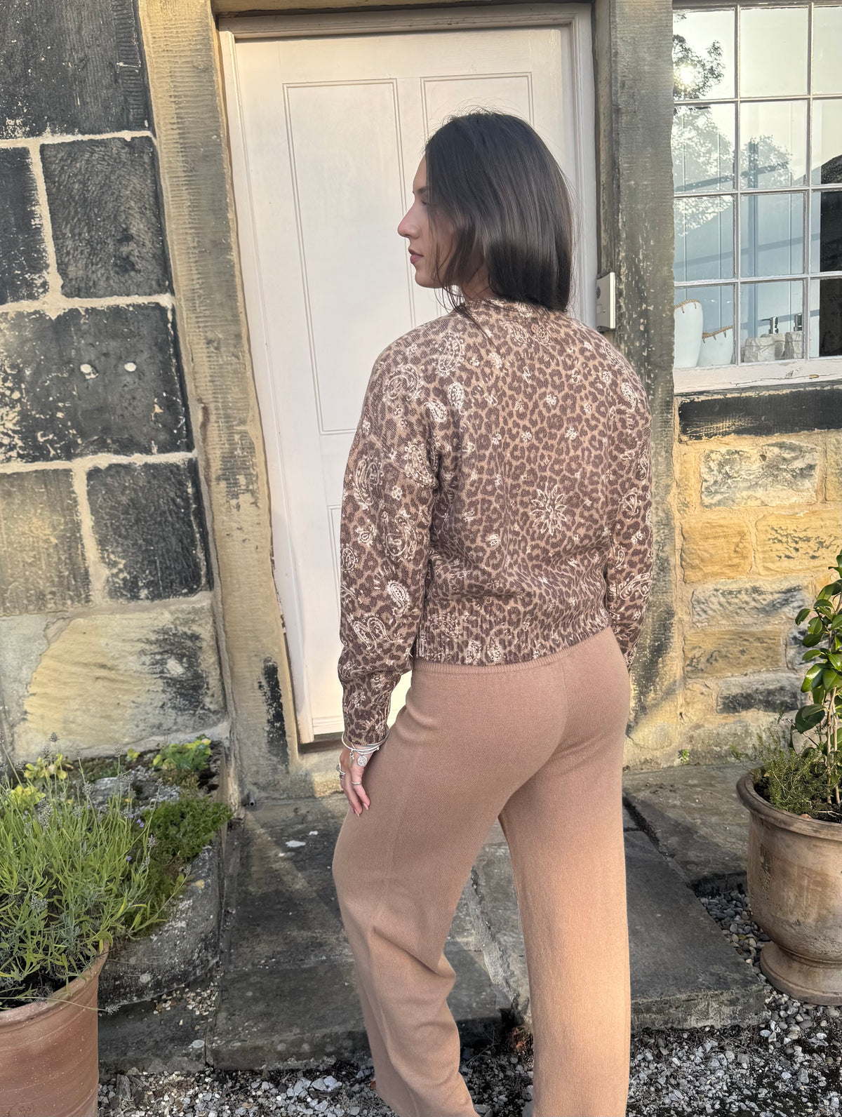 Woman wearing camel wool knit trousers with relaxed fit back view