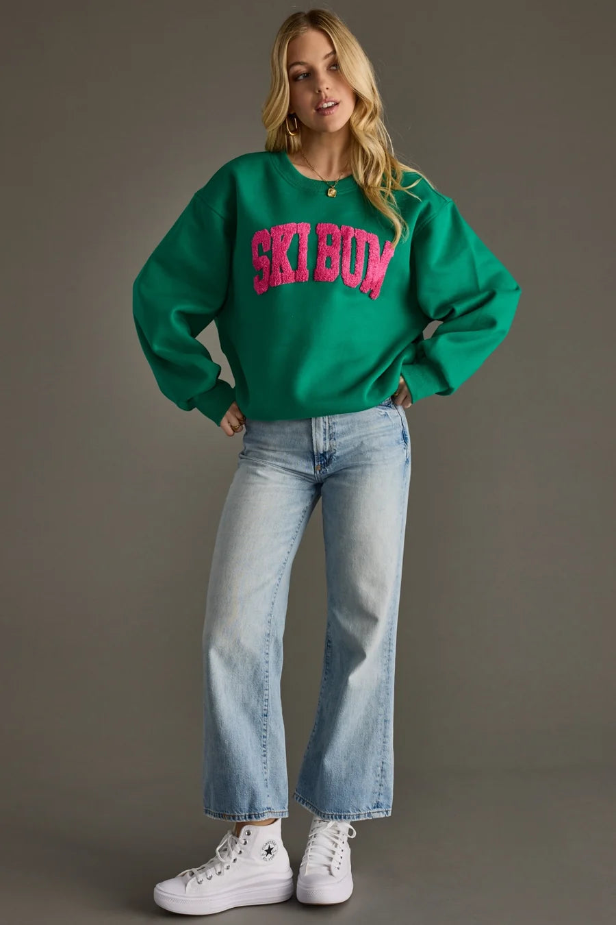 Oversized green sweatshirt featuring a bold pink “SKI BUM” patch and relaxed casual silhouette.