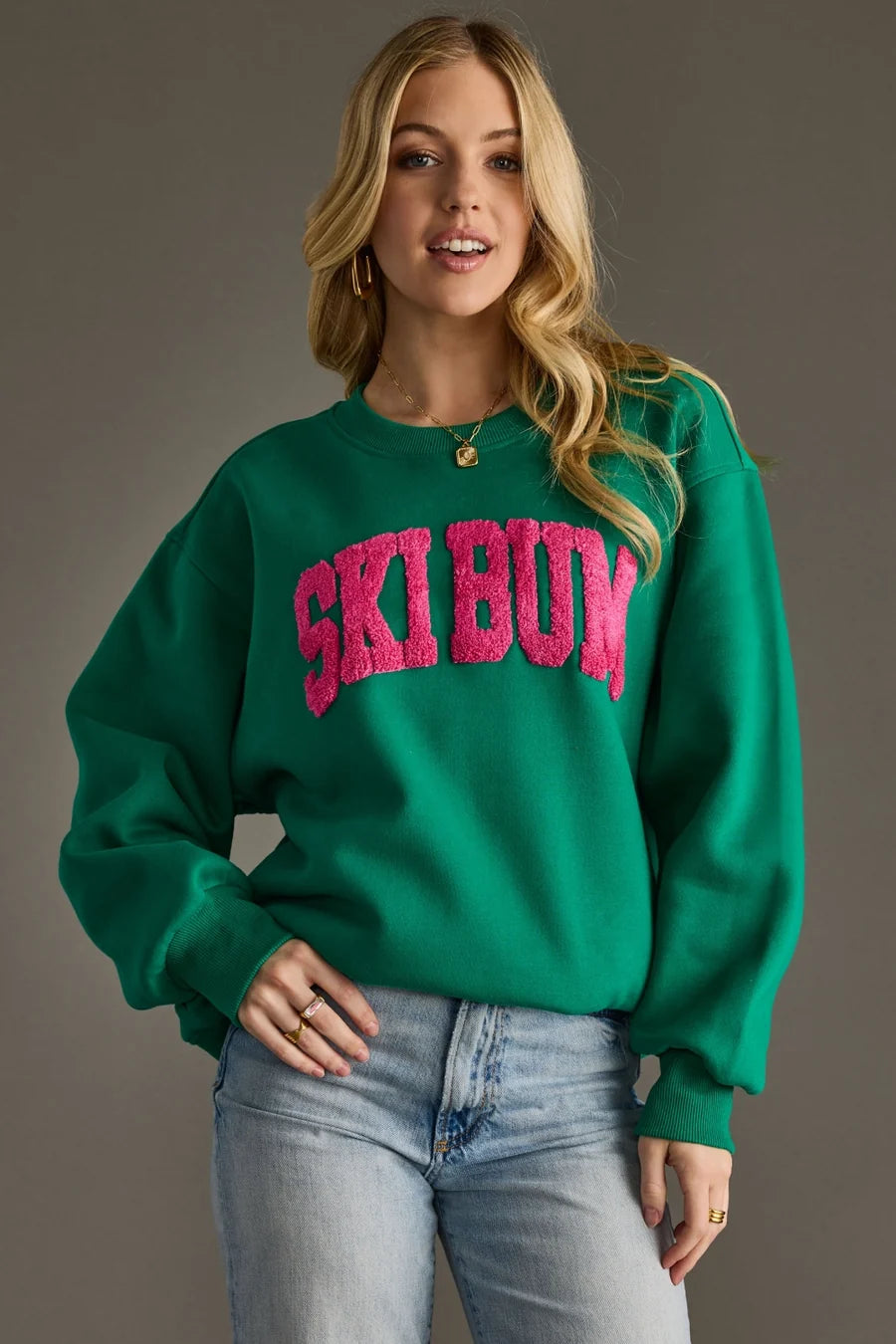 Green Ski Bum sweatshirt with a hot pink varsity-style patch, oversized fit and ribbed cuffs and hem.