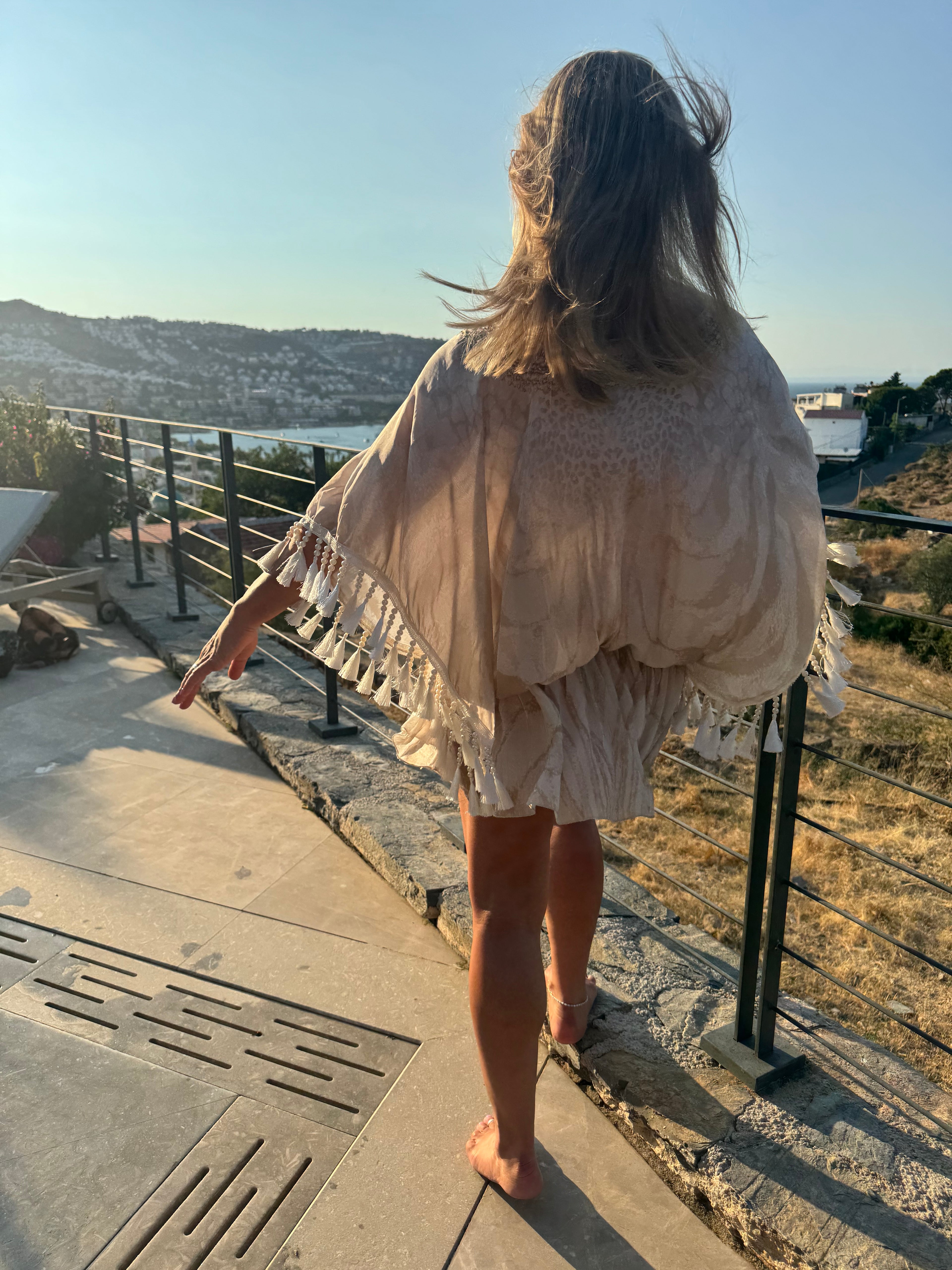 Cream holiday kaftan with a semi-sheer animal print, flowing batwing sleeves and layered beaded tassel fringe