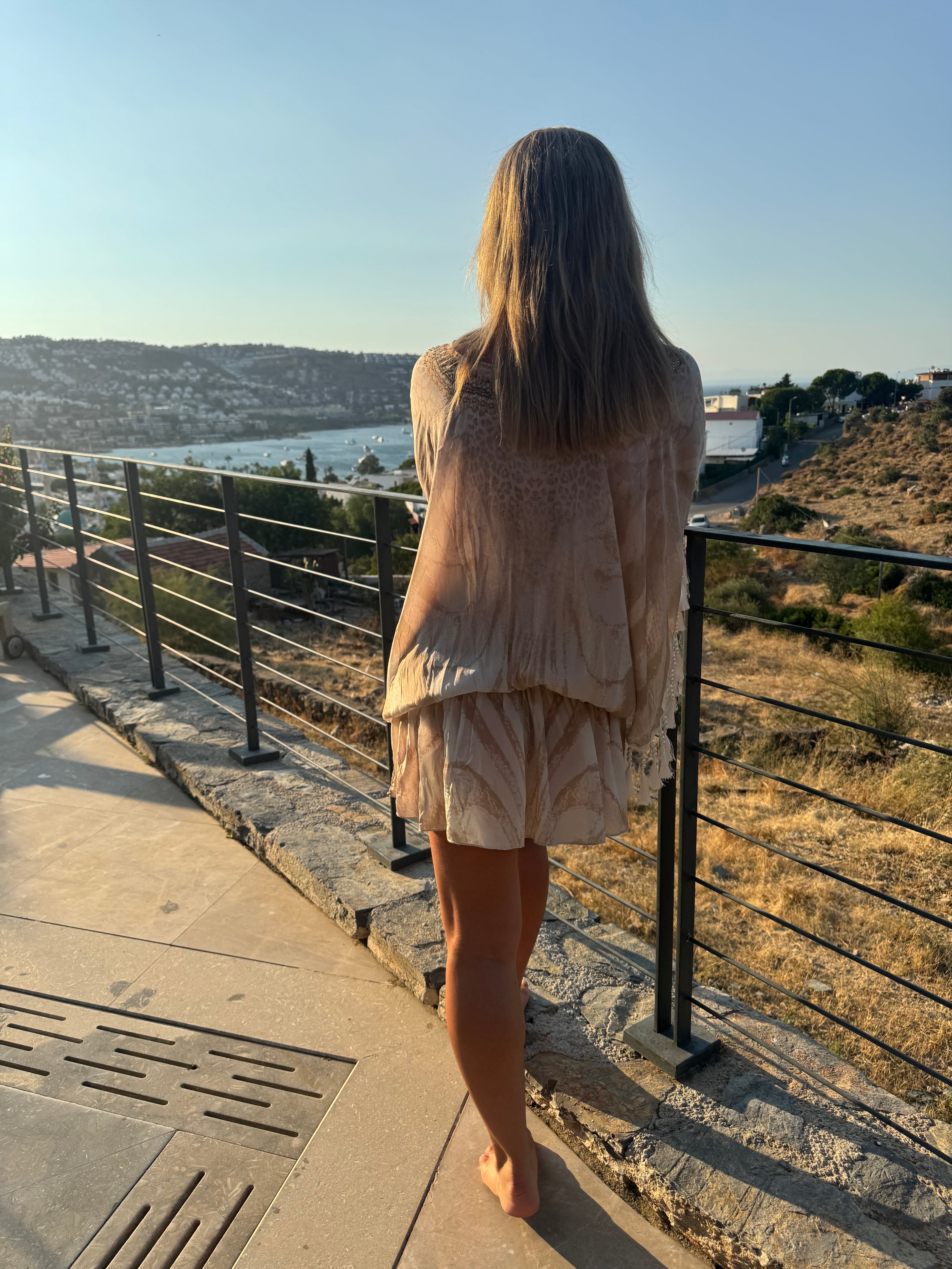 Cream holiday kaftan with a flowing semi-sheer fit, tonal abstract pattern, wide sleeves and beaded tassel trim.