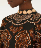 Close-up of copper, gold and blue baroque print on black mini dress hem