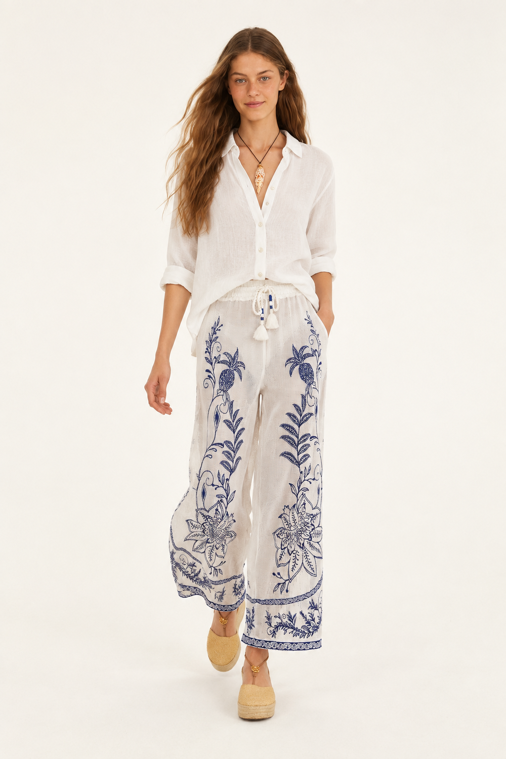 Model walking in off-white Nina pants with navy floral embroidery and wide legs